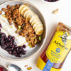 Yogurt bowl with granola, berries, and banana slices next to a jar of Airborne Manuka Honey.